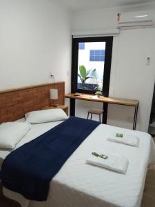 um quarto com 2 camas, uma secretária e uma janela em Requinte Hotel em São Paulo