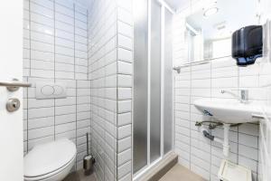 a white bathroom with a toilet and a sink at Adagio Hostel Basilica in Budapest