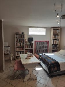 Schlafzimmer mit einem Bett, einem Tisch und Bücherregalen in der Unterkunft Sotto Sotto in Viareggio