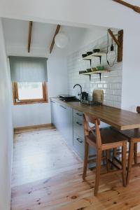 a kitchen with a wooden table and a wooden chair at Weź tu Przystań - Mikołajek 1 in Pomiechówek