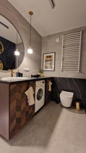 a bathroom with a sink and a washing machine at Lenki apartamenty Białołęka in Warsaw