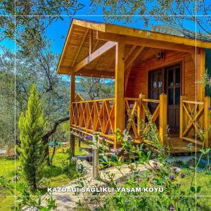 uma cabana de madeira na floresta com um alpendre em Kazdağları Sağlıklı Yaşam Köyü em Edremit