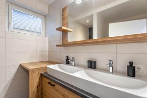 ein weißes Badezimmer mit einem Waschbecken und einem Spiegel in der Unterkunft Apartment mit Blick auf die Berge in Rettenstein