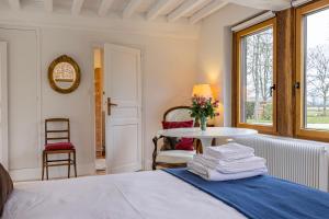 Maison "Le Pressoir" avec Grand Jardin في Biéville-en-Auge: غرفة نوم بسرير وطاولة مع مناشف