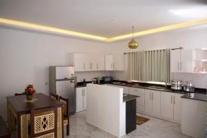 a large kitchen with white cabinets and a refrigerator at Arbian Valla in Dahab