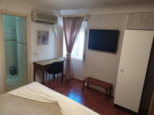 Schlafzimmer mit einem Bett, einem Schreibtisch und einem TV in der Unterkunft Residencial Carvalho in Estremoz
