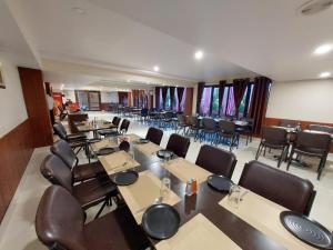 a conference room with tables and chairs and windows at Hotel Vrinda in Maihar