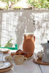 een tafel met een kruik en enkele kopjes en croissants bij Villa Aimone in Marina Porto