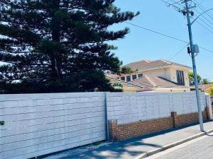 a white fence in front of a house at Le Lieu Accommodation in Cape Town