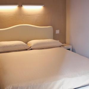 Una cama blanca con dos almohadas encima. en Agriturismo Pozzuolo, en Serrungarina