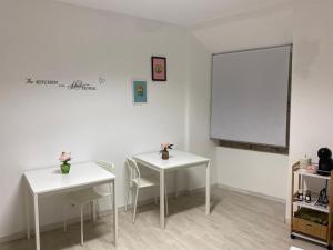 2 mesas y sillas en una habitación con una pared blanca en 5 Senses Hostel, en Setúbal