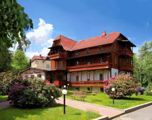 ein großes Gebäude mit einer Bank davor in der Unterkunft Hotel Narcyz in Świeradów-Zdrój