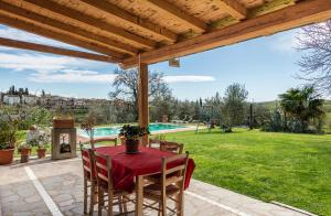 un patio con mesa, sillas y piscina en Alloggio incantevole con piscina, en Vinci