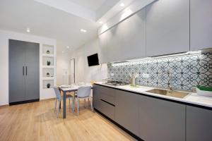 Una cocina con gabinetes blancos y una mesa con sillas. en Victoria Apartments Family, en Diano Marina
