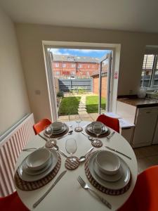 a white table with plates and silverware on it at Kingmaker House! Luxury 4 Beds - Free Private Parking and Garden in Northampton