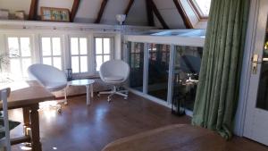 een woonkamer met stoelen en een tafel en ramen bij De Geheime Tuin - Uitzicht in Epe