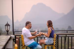 Ein Mann und eine Frau sitzen an einem Tisch mit einem Glas Wein. in der Unterkunft Confetti Garden Hotel in Vang Vieng