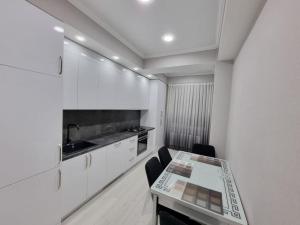 キシナウにあるComfortable Luxury Apartments in Centerの白いキャビネットとテーブルと椅子のあるキッチン