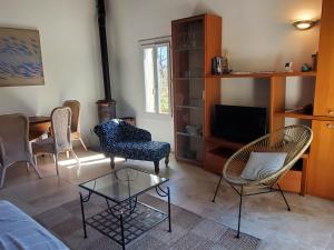 a living room with chairs and a table and a tv at Gîte Le Petit Jas in Villeneuve