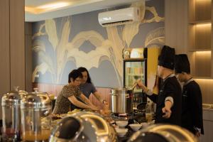 un grupo de personas en una cocina preparando comida en Confetti Garden Hotel en Vang Vieng