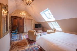 a bedroom with a bed and chairs in a attic at Domaine de Charnay Villégiature Sologne in Vierzon