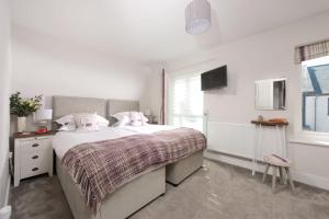 um quarto branco com uma cama grande e uma janela em Wish You Were Here, Crantock em Newquay