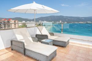 eine Terrasse mit Stühlen und einem Sonnenschirm auf dem Dach in der Unterkunft Seramar Hotel Comodoro Playa in Palmanova