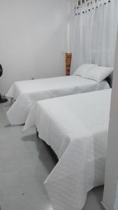 2 camas con sábanas blancas en un dormitorio en Mangüeña Alojamiento Rural en Santa Rosalía de Guagua