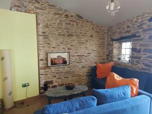 a living room with a blue couch and a stone wall at Casa Maruja, Puebla de Sanabria in Puebla de Sanabria