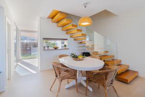 una sala da pranzo con tavolo e sedie bianchi e una scala di Villa Blue Sagres G a Sagres