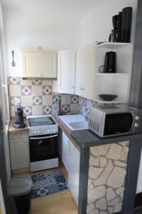 eine kleine Küche mit einem Herd und einer Mikrowelle in der Unterkunft laureclipse2 in Mers-les-Bains