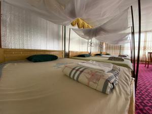 a bedroom with two beds with a canopy at Tom Homestay in Yên Minh