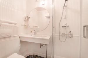 ein weißes Bad mit einem Waschbecken und einer Dusche in der Unterkunft Pensjonat & Restauracja Admirał in Jastarnia