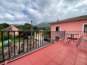 Un balcón de una casa rosa con una mesa en La Casa de Anita y José, en Colunga