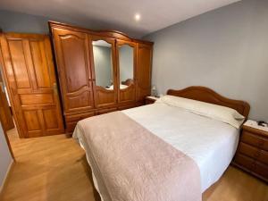 1 dormitorio con 1 cama grande y armarios de madera en La Casa de Anita y José, en Colunga