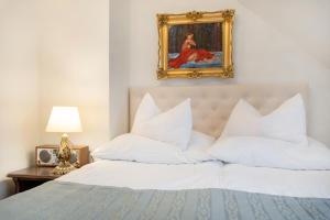 1 cama con almohadas blancas y una pintura en la pared en Pensjonat & Restauracja Admirał, en Jastarnia