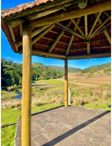 a wooden pavilion with a view of a field at Casa de campo cânions in São Gonçalo