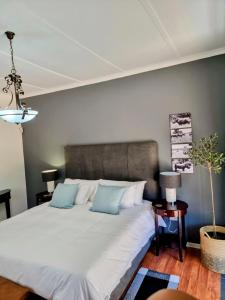a bedroom with a large white bed with blue pillows at Sonskyn Hof Guest House / Gastehuis in Jan Kempdorp