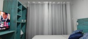 a bedroom with a bed and a green book shelf at Studio e Suite no Centro de Juquehy a 150mts da praia - Varanda e Serviço de Praia --- E MAIS Ofurô - Cozinha e Estacionamento nas unidades "STUDIO" -- TUDO NOVO in Juquei