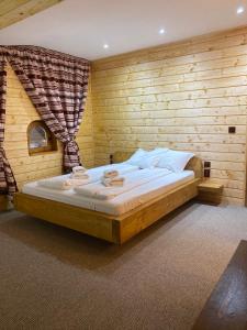 a bedroom with a large bed in a wooden wall at Căsuța din Povești in Horea