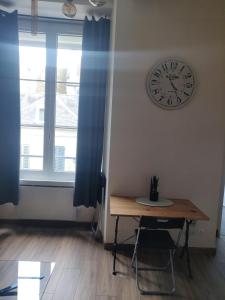 una habitación con un reloj en la pared y una mesa en La porte St Georges, le centre ville en Vendôme