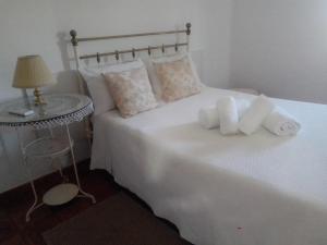 um quarto com uma cama branca com almofadas e um candeeiro em Casas da Saibreira - nº2 em Elvas