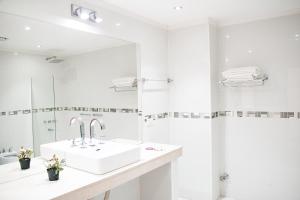 uma casa de banho branca com um lavatório e um espelho em SOMMER Y SOL em Cafayate