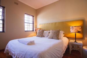 a bedroom with a white bed with two windows at Swellendam Self Catering in Swellendam