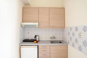 a small kitchen with wooden cabinets and a sink at Sunny Apartments - ex Zoi Studios in Agioi Apostoli