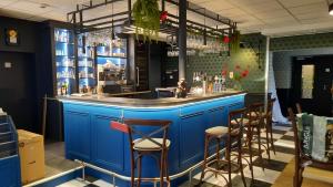 un bar azul en un restaurante con taburetes en L'Auberge des Artistes, en Nieul-sur-lʼAutise