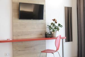 Habitación con silla roja y TV en la pared. en L'Insolito Posto, en Sabbioncello