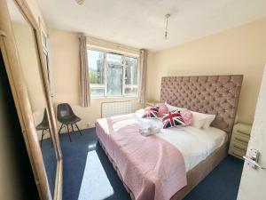 1 dormitorio con 1 cama grande con mantas y almohadas rosas en Flat 21, en Londres