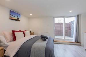 a bedroom with a large bed and a large window at Central Windsor Modern Garden Flat, Walk 2 Sights in Windsor