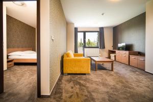 Pokój hotelowy z żółtym krzesłem i łóżkiem w obiekcie Hotel Panorama Resort w Szczyrbskim Plesie